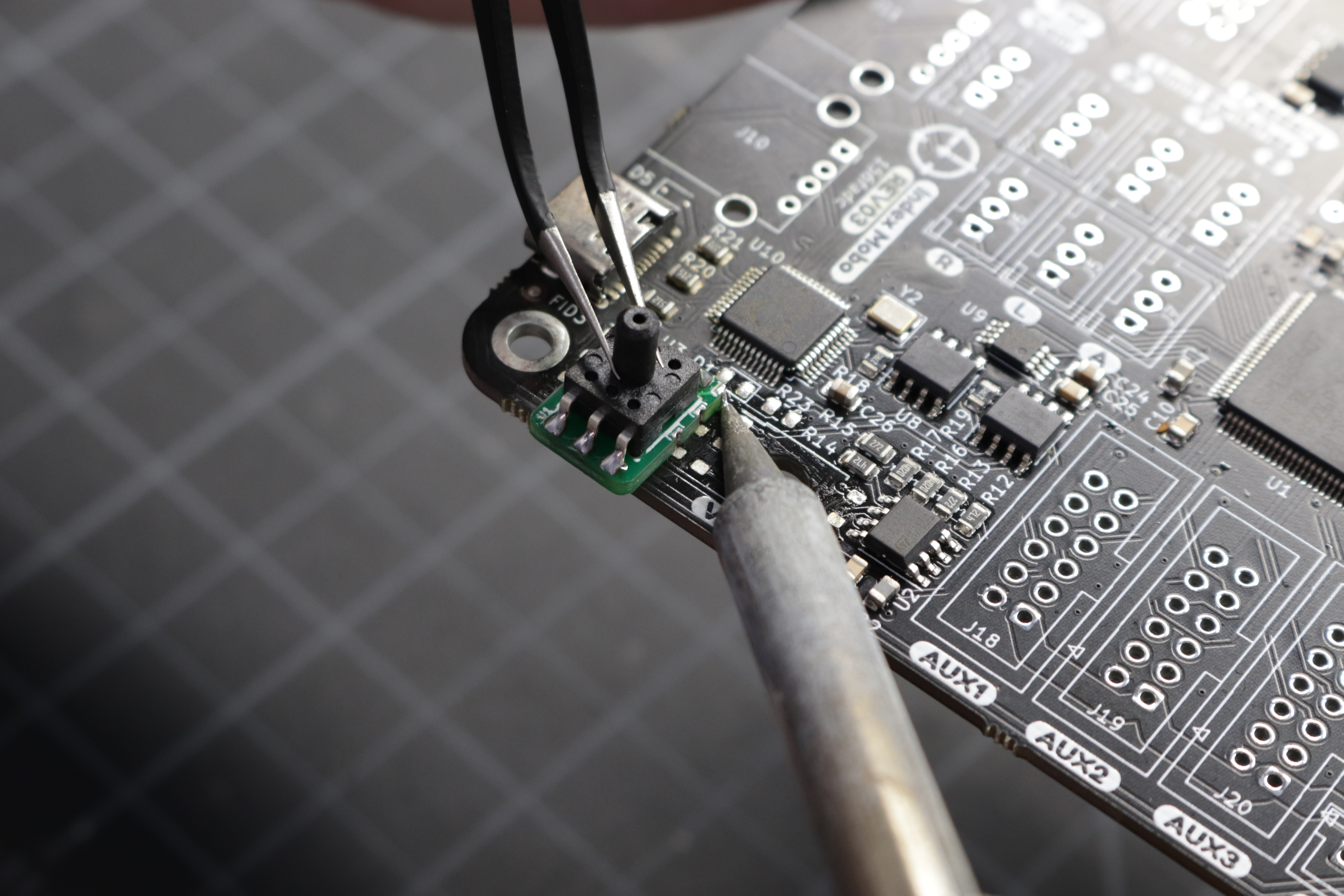 A photo of the interposer board held in place using the one soldered pad